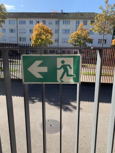 Langnachleuchtendes Fluchtwegschild nach ISO 7010 auf Geländer im Aussenbereich montiert.